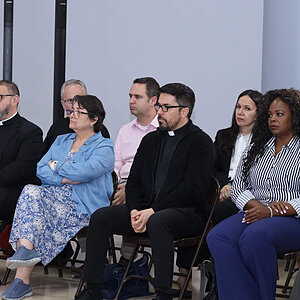 Clergy and laypeople sit attentively, facing forward.